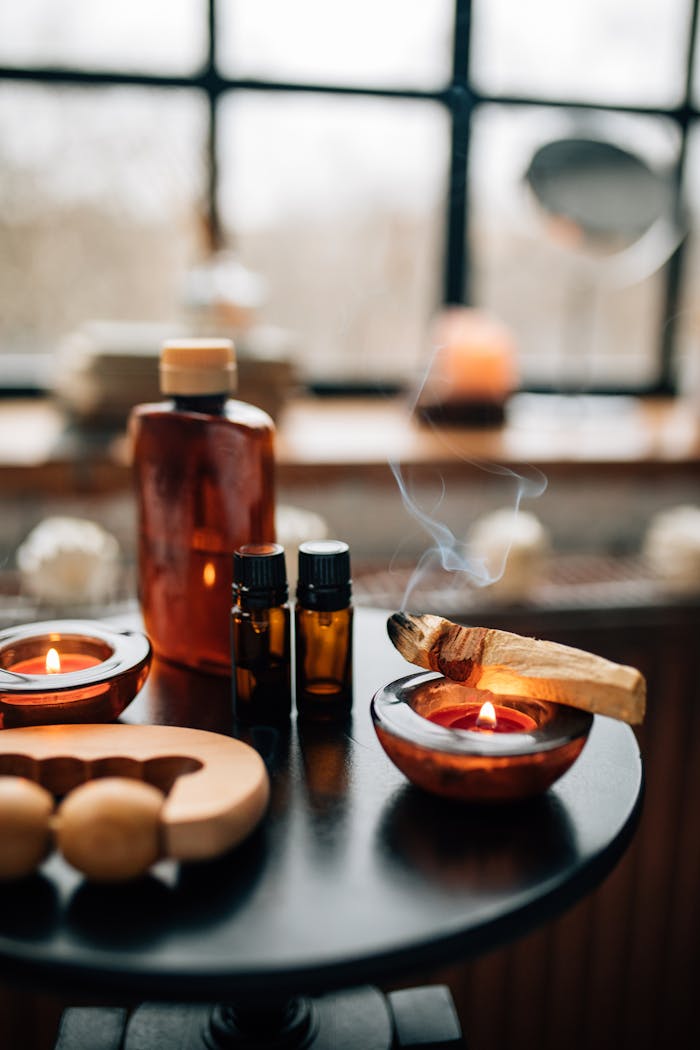 A calming indoor aromatherapy scene featuring candles, bottles, and burning Palo Santo, perfect for relaxation.
